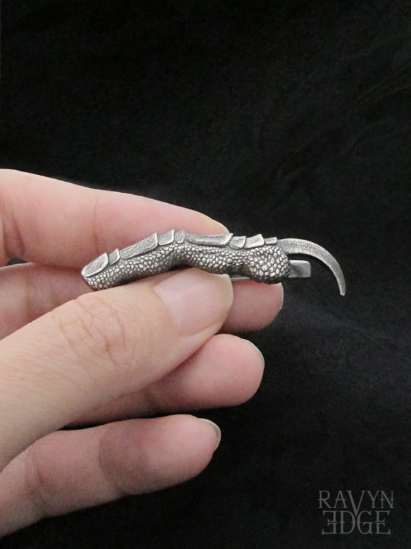 Hand holding a silver dragon claw mens tie bar