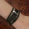 Tiny sterling silver raven skull charm on a black leather wrap bracelet