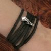 Leather wrap bracelet with tiny silver raven skull on a womans wrist