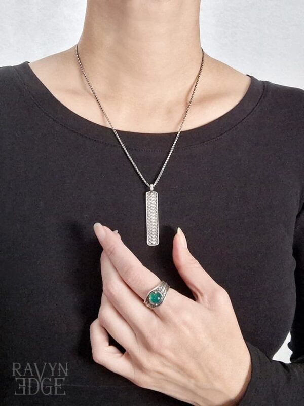 Woman wearing dragon scale jewelry. A silver vertical bar necklace and a ring with green onyx.