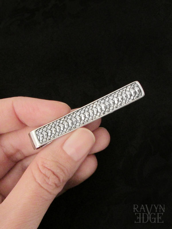 Hand holding a silver dragon scale mens tie bar