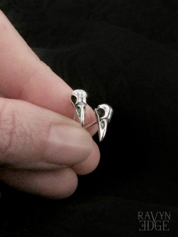 Small silver stud earrings shaped like little raven skulls