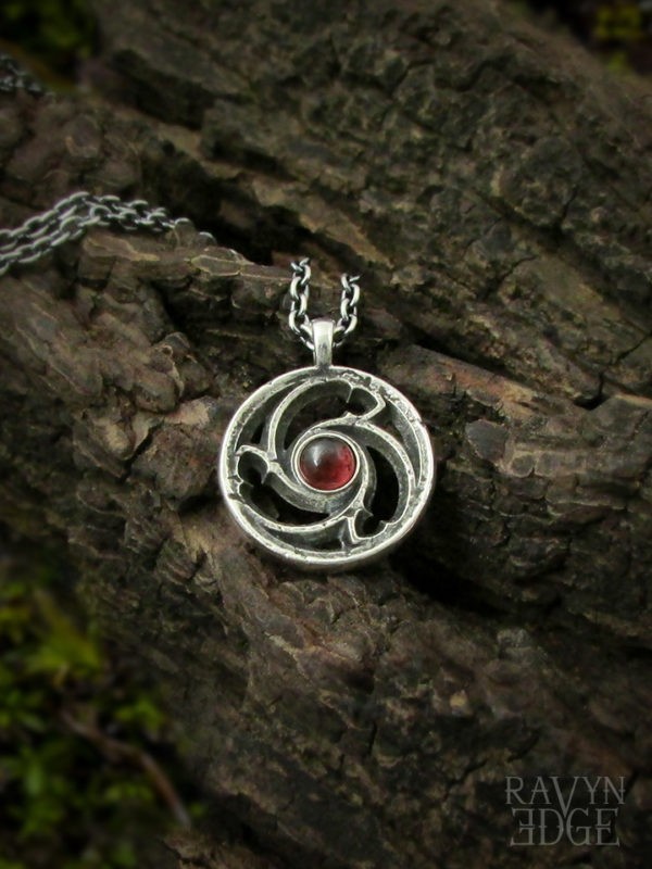 Small triskele window necklace in sterling silver with garnet